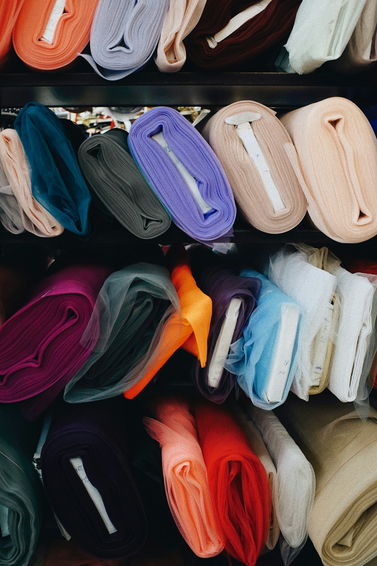Rolls of fabric in many colours stacked on shelves