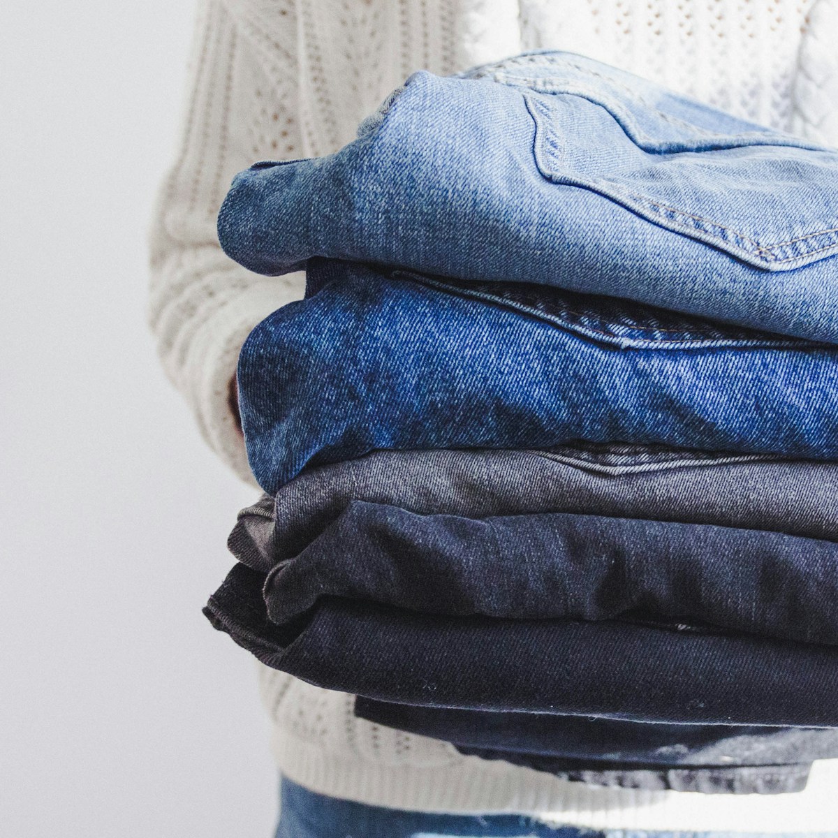 A person holding a stack of folded denim