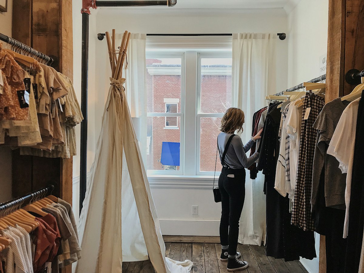 A person browsing clothes on a rail in a shop