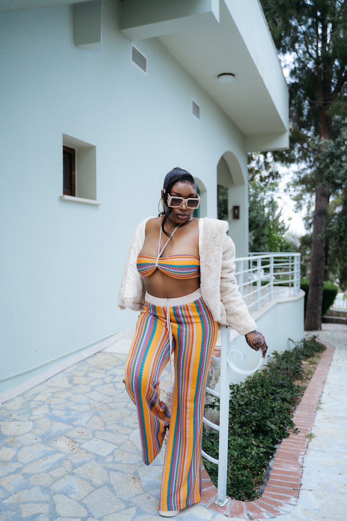 A bold striped knit co-ord styled with a cream jacket and sunglasses