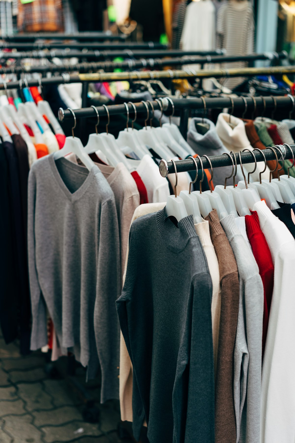Rails of jumpers and cardigans on hangers, sorted by colour