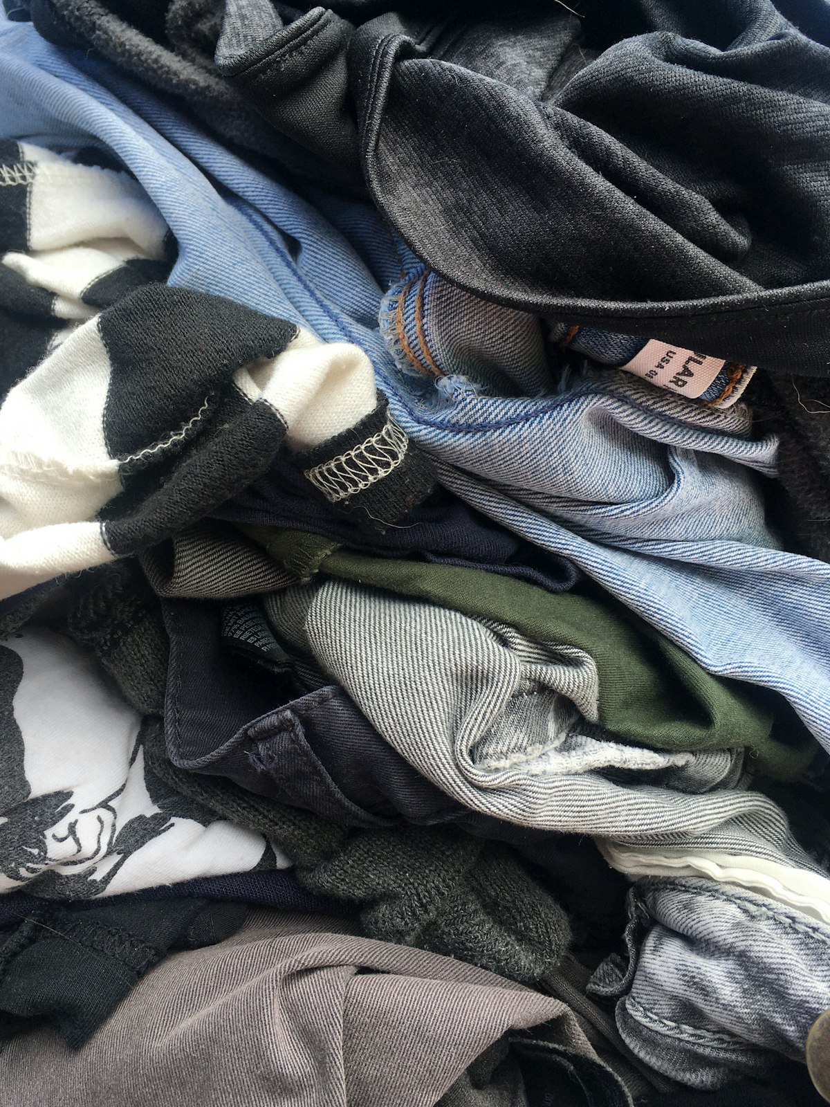 A pile of jeans, knitwear and T-shirts waiting to be sorted