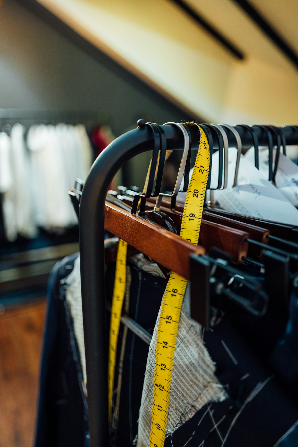 Tape measures hanging over a rail of clothes on hangers