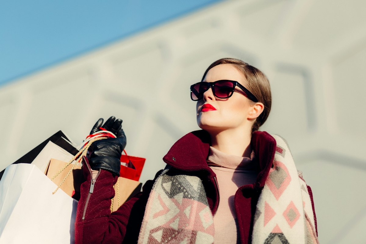 A person in sunglasses carrying several shopping bags