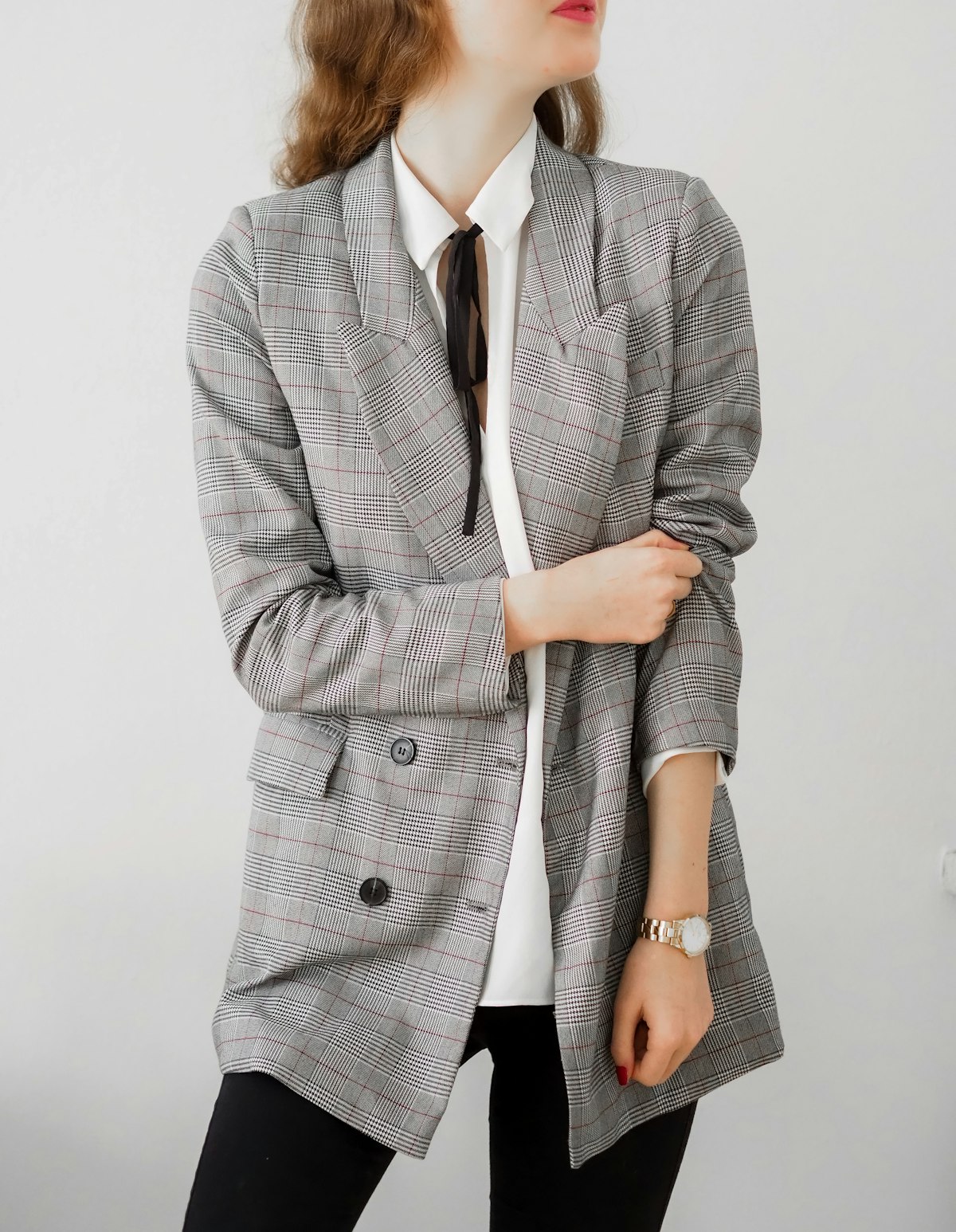 A person in a grey check blazer over a white shirt and black trousers